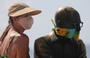 Uma mulher posa para uma foto ao lado da estátua do escritor brasileiro Carlos Drummond de Andrade que usa uma máscara protetora no primeiro dia de uso obrigatório de máscaras em meio ao surto de doença por coronavírus (COVID-19), na praia de Copacabana - Reuters/Sergio Moraes/Direitos Reservados