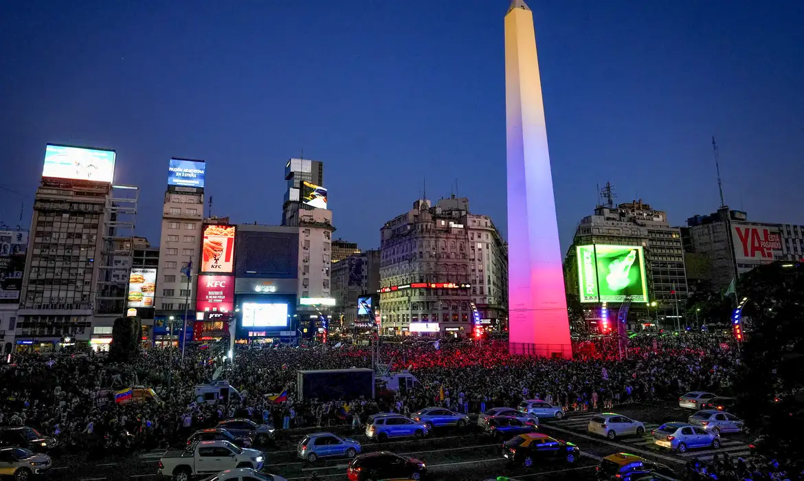 O ataque dos Estados Unidos que resultou na captura do presidente da Venezuela, Nicolás Maduro, na madrugada de sábado (3), levou manifestantes às ruas em diversas cidades do mundo neste fim de semana, incluindo venezuelanos que migraram para outros países em busca de melhores condições de vida. Além de levar Maduro e a primeira-dama, Cilia Flores, para serem julgados nos Estados Unidos, por um suposto envolvimento com o tráfico internacional de drogas, o governo americano anunciou que pretende administrar a Venezuela "até que se possa realizar uma transição segura, adequada e criteriosa". O presidente dos Estados Unidos, Donald Trump, também afirmou que empresas americanas passarão a controlar o setor de petróleo do país, que tem as maiores reservas confirmadas de óleo e gás do mundo. Segundo a agência de notícias Reuters, houve atos de venezuelanos neste fim de semana comemorando a ação dos Estados Unidos em uma série de países latino-americanos e também na Espanha, em cidades como Bogotá, Lima, Quito e Madrid. Na Cidade do México, venezuelanos e mexicanos a favor e contra a ação militar norte-americana organizaram atos em frente às embaixadas da Venezuela e dos Estados Unidos, com críticas ao intervencionismo ou celebrações de que o país estava livre de Maduro. A polícia precisou intervir para evitar o aumento da tensão entre os grupos. Em Buenos Aires, na Argentina, movimentos sociais e venezuelanos contrários à ação protestaram no sábado, em frente à embaixada dos Estados Unidos, enquanto outro grupo se reuniu no Obelisco para comemorar a captura de Maduro. Também houve protestos contra o ataque nos Estados Unidos, em cidades como São Francisco e Nova York, além do registro de grupos de venezuelanos que celebraram a ação. People celebrate following a U.S. strike on Venezuela, where President Nicolas Maduro and his wife, Cilia Flores, were captured, in Buenos Aires, Argentina, January 3, 2026. REUTERS/Mariana Nedelcu Pessoas celebram ação dos Estados Unidos em protesto em Buenos Aires, na Argentina REUTERS/Mariana Nedelcu Diáspora Cerca de 20% da população da Venezuela deixou o país desde 2014, e os principais destinos foram a Colômbia, que recebeu 2,8 milhões de venezuelanos, e o Peru, que recebeu 1,7 milhão, de acordo com a plataforma R4V, um grupo de ONGs regionais que prestam assistência a migrantes e refugiados da Venezuela, criada pela agência de migração da ONU. Há três anos na Espanha, país que recebeu 400 mil venezuelanos, Andrés Losada disse à Reuters que está lutando entre a preocupação e a alegria com a situação na Venezuela. "Embora o que as pessoas estejam passando em Caracas seja difícil, acredito que, além disso, há uma luz que nos levará à liberdade", acrescentou. Em Quito, capital do Equador, a venezuelana Maria Fernanda Monsilva disse esperar que Edmundo González, o principal candidato da oposição venezuelana na eleição presidencial de 2024, possa assumir o poder. "Muitos de nós que estamos no exterior queremos voltar", disse Monsilva. Apesar da declaração do governo americano de pretende controlar a Venezuela, o Supremo Tribunal de Justiça da Venezuela (TSJ, na sigla em espanhol) decidiu que a vice-presidente executiva Delcy Rodríguez deverá assumir a presidência interina do país. Brasília (DF), 04/01/2026 - Venezuelan diaspora in Mexico divided over U.S. action, police intervene to separate groups Frame Reuters/Proibida reprodução Manifestantes contrários ao ataque protestam na Cidade do México. Frame Reuters/Proibida reprodução Em Caracas, capital da Venezuela e cidade que foi alvo do ataque, uma manifestação repudiou a intervenção americana. O venezuelano José Hernandez participou do protesto e classificou de criminosa a operação estrangeira em seu país. “Os outros países do mundo precisam ter muita clareza sobre o modo completamente criminoso com que os Estados Unidos estão agindo. Isso é extrair, ou melhor, roubar recursos de outros países que têm energia e minérios”, criticou.