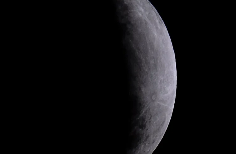 Lua cheia no céu noturno com a sombra da Terra cobrindo parcialmente a sua superfície durante o eclipse.