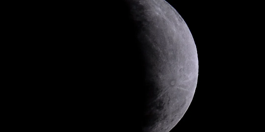 Lua cheia no céu noturno parcialmente encoberta pela sombra escura da Terra durante eclipse lunar