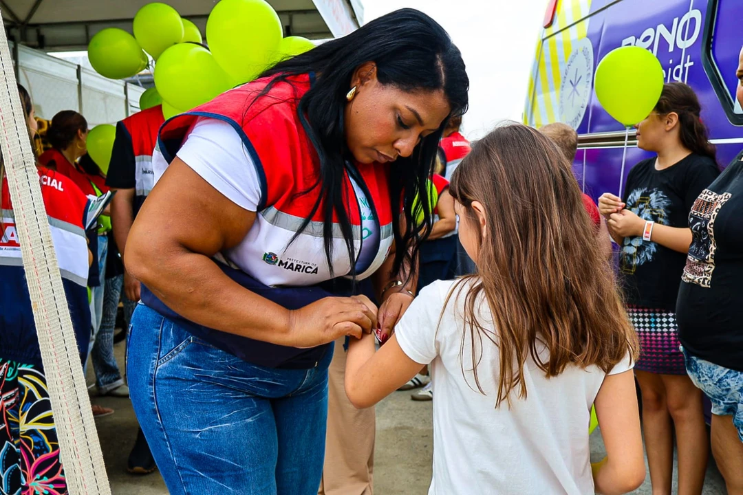 Profissional da Assistência Social realizando o cadastramento e identificação de uma criança durante evento público em Maricá