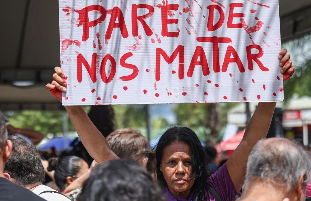 Manifestantes segurando cartazes que exigem punição para agressores de mulheres políticas