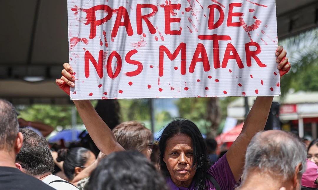 Manifestantes segurando cartazes que exigem punição para agressores de mulheres políticas