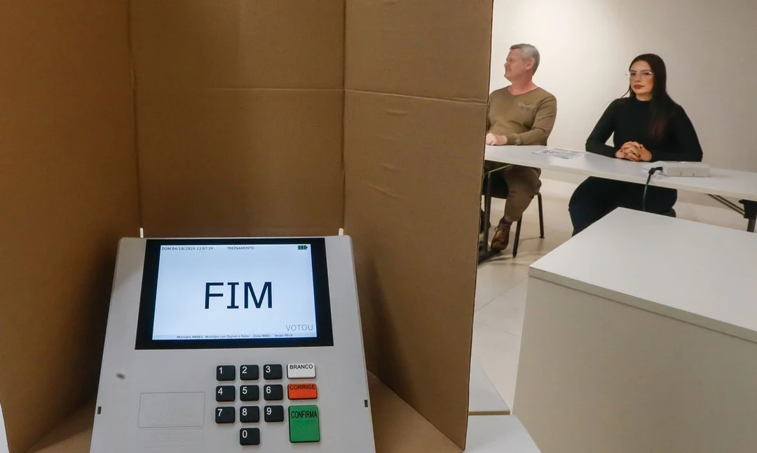 Eleitor entregando celular à mesa receptora antes de entrar na cabine de votação