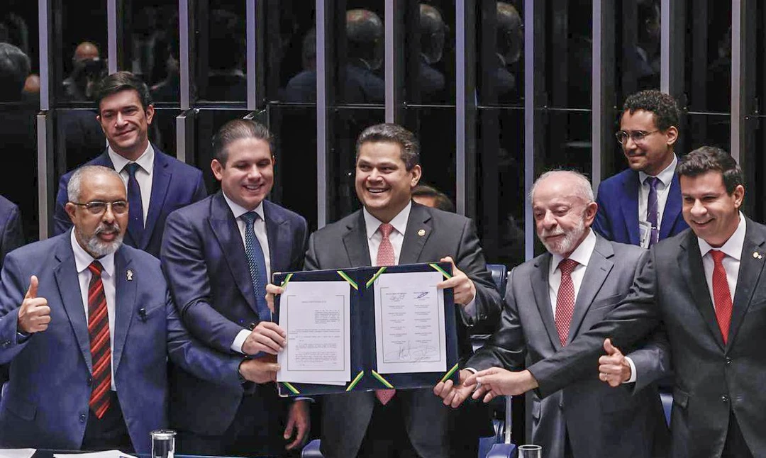 Senador Davi Alcolumbre convidando o senador Paulo Paim a sentar‑se à mesa oficial durante a promulgação da emenda que encerra a escala 6x1