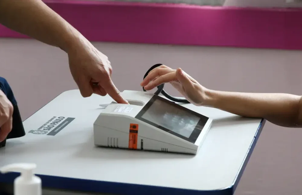 Eleitor utilizando leitor biométrico nas urnas eletrônicas