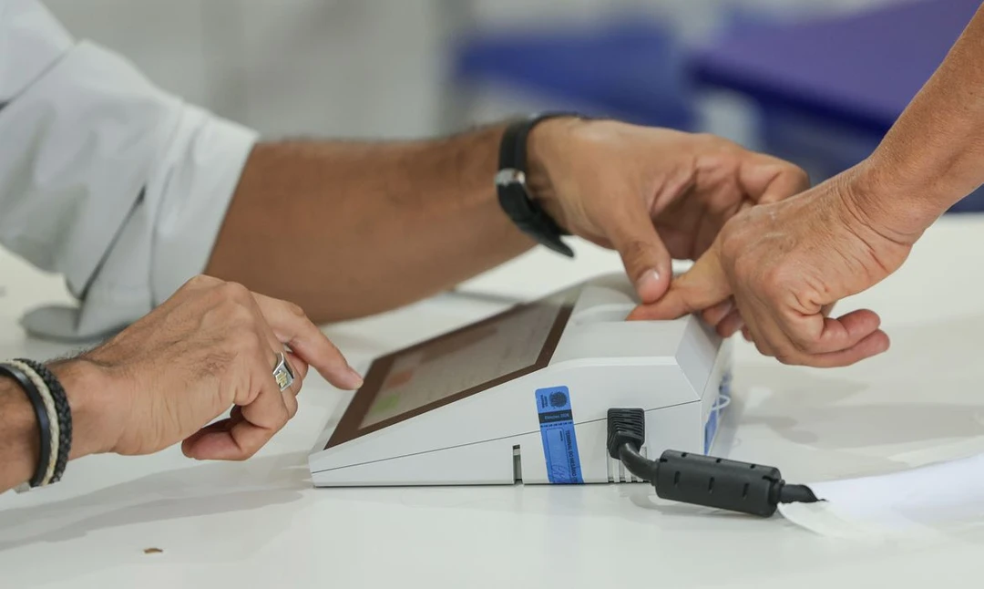Eleitor brasileiro inserindo voto na urna eletrônica durante as eleições presidenciais de 2026