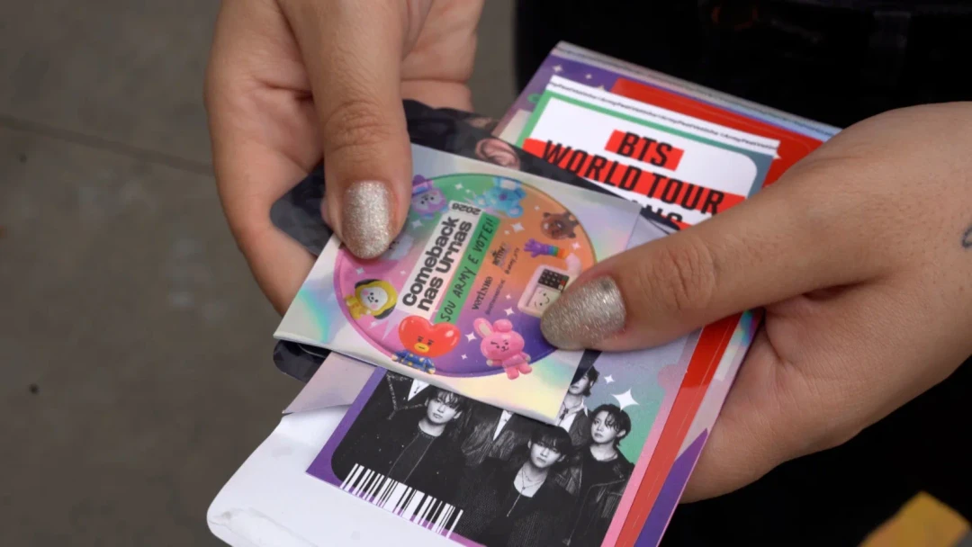 Fãs do BTS exibindo comprovante de votação para receber mystery pack durante concerto em São Paulo
