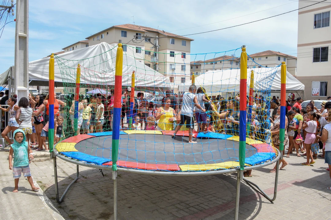 Crianças participando das atividades do programa Dia das Crianças nas comunidades de Maricá, com brinquedos infláveis e apresentações artísticas